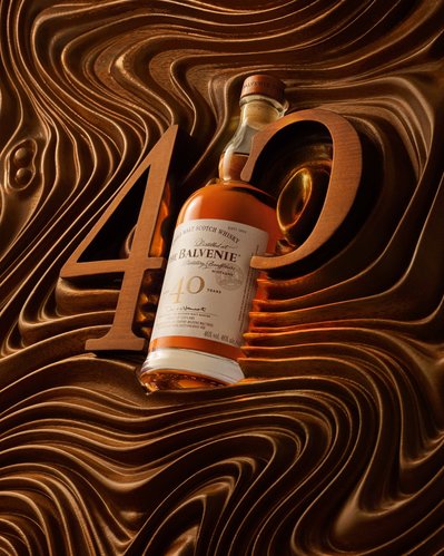A creative composition showcasing a wine bottle strategically placed between the numerals 4 and 0, delicately inscribed on a wooden surface. This visually appealing image is skillfully captured by David Lineton, an expert drinks advertising photographer 
