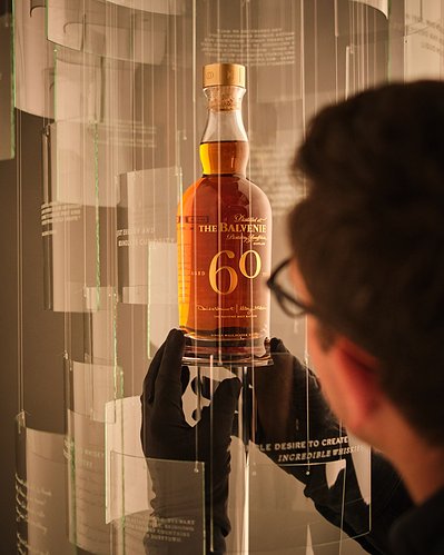 Behind the scenes of David Lineton Still Life Photographer on The Balvenie 60 Years Campaign adjusting the Hero bottle within set wearing gloves