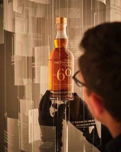Behind the scenes of David Lineton Still Life Photographer on The Balvenie 60 Years Campaign adjusting the Hero bottle within set wearing gloves