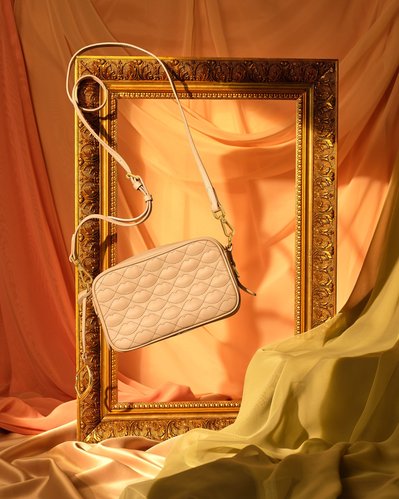 A stylish composition featuring a small purse elegantly hung alongside an empty photo frame cover. Skillfully captured by David Lineton, an expert accessories photographer in London.