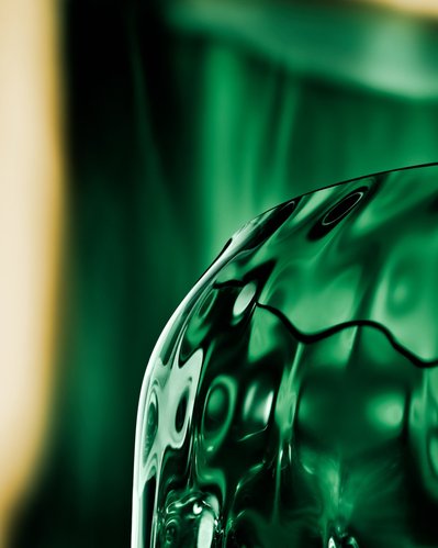 A detailed close-up view capturing one side of a greenish glass against a backdrop of green surroundings and a greenish background. Expertly captured by David Lineton, a specialist in still life object photography in London