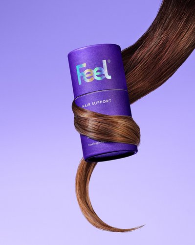 A captivating image of Hair Support Product, featuring strands of a girl's hair elegantly draped across the product, creating a visually dynamic composition, skillfully captured by David Lineton, a distinguished beauty photographer
