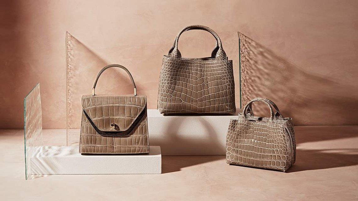 Three Leather Handbags photographed on a plaster toned background with shafts of cut glass panels creating refraction to the light