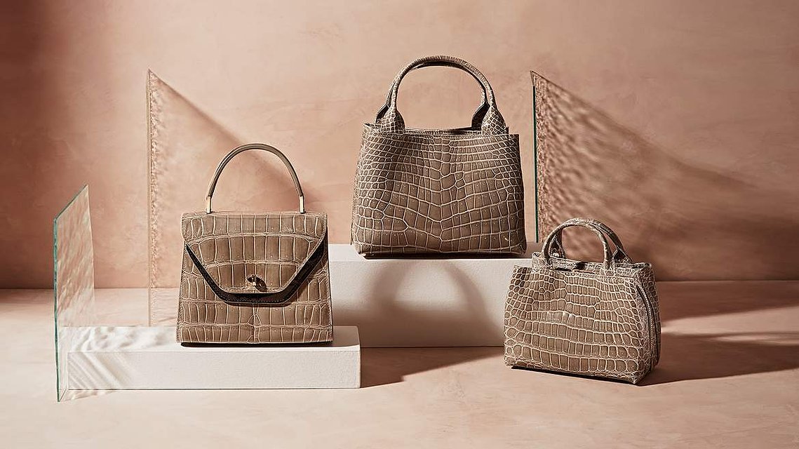 Three Leather Handbags photographed on a plaster toned background with shafts of cut glass panels creating refraction to the light