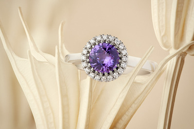 A stunning ring featuring a big purple stone surrounded by small white stones, elegantly placed on a stylish surface. This visually captivating composition is skillfully photographed by David Lineton, an expert in jewelry photography services in London