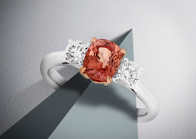 A beautiful ring adorned with a red gemstone and two white pearls elegantly positioned on top. This visually appealing composition is skillfully photographed by David Lineton, an expert in luxury product photography.