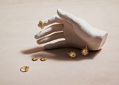 A compelling composition featuring a piece of jewelry presented on a surface, with one ring delicately placed on the finger of a cut statue hand. skillfully photographed by David Lineton, an expert in commercial jewelry photography in London