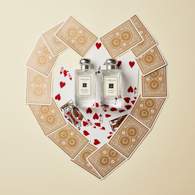 A captivating composition featuring two perfume bottles elegantly surrounded by cards arranged in the shape of a heart. This visually appealing image is skillfully photographed by David Lineton, an expert in perfume commercial photography in London. 