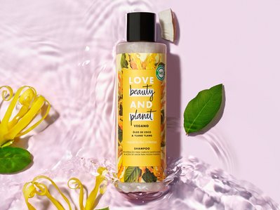 A captivating image featuring Love Beauty and Planet shampoo, gracefully placed in a vibrant pink fluid with scattered leaves, creating a scene of natural beauty. This visually pleasing composition is skillfully captured by David Lineton. 