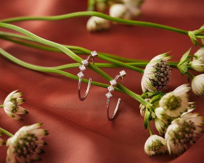 A charming composition featuring two rings creatively positioned with a flower base threading through them. This visually delightful arrangement is skillfully photographed by David Lineton, an expert in professional jewelry photography in London