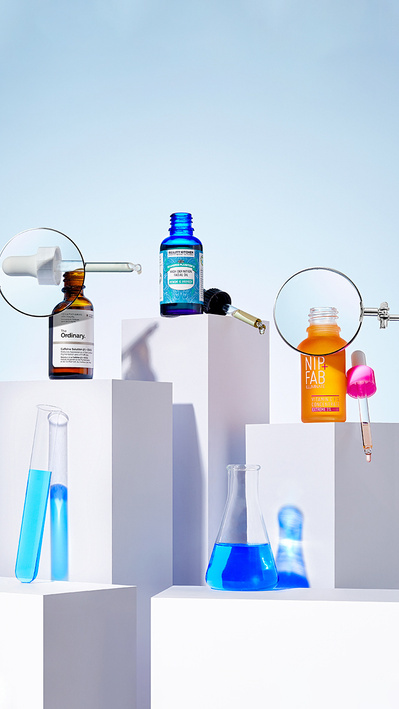 A striking presentation featuring a blue serum product positioned against a backdrop divided into two contrasting halves. This captivating composition is skillfully photographed by David Lineton, an expert in cosmetics photography. 