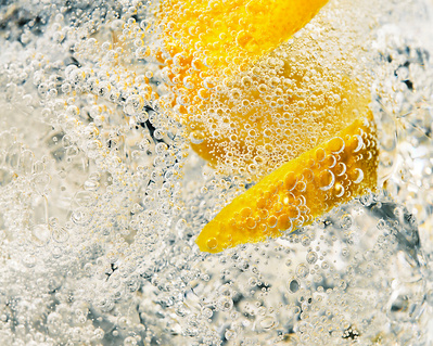 A close-up photograph capturing the details of a drink glass, with visible bubbles and a neatly cut lemon inside. This refreshing image is skillfully photographed by David Lineton, an expert in drinks photography in London.