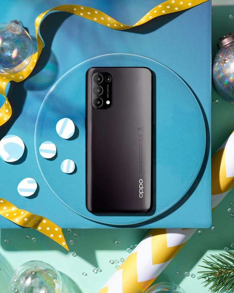 Oppo Phone Christmas gift guide still life image. The technology with the three cameras makes for a striking back to this phone. The Blue background and yellow highlights of the wrapping paper makes the phone pop