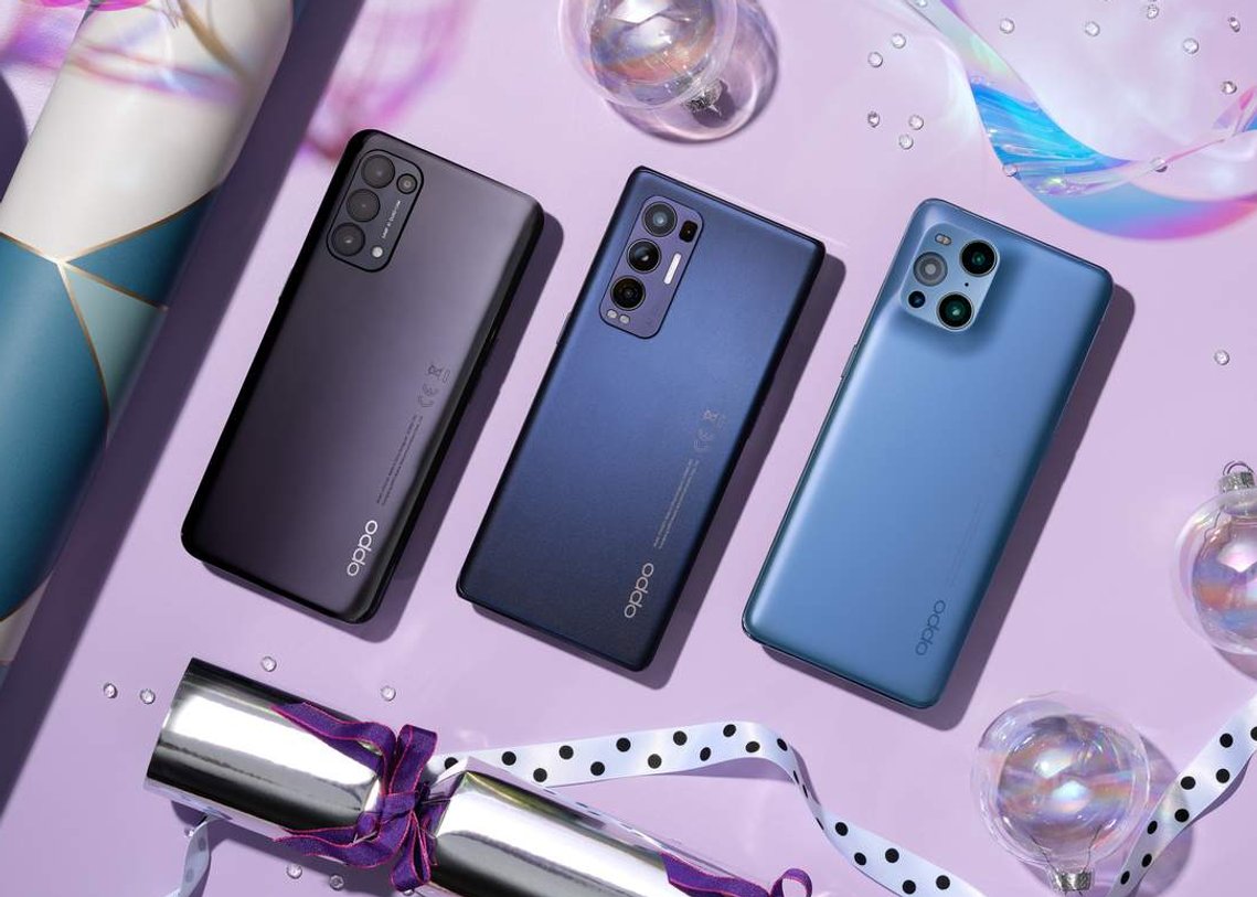 Three Oppo Phones surrounded by ultraviolet pink set with festive touches of baubles, sequins, ribbon and wrapping paper.