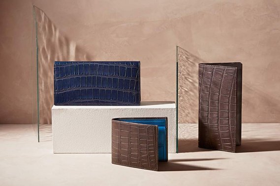 Small leather Purses and wallets by Hanuxe Leather photographed on a real plaster surface with art glass creating interest in the high key daylight lighting