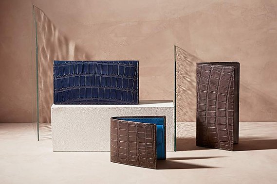 Small leather Purses and wallets by Hanuxe Leather photographed on a real plaster surface with art glass creating interest in the high key daylight lighting