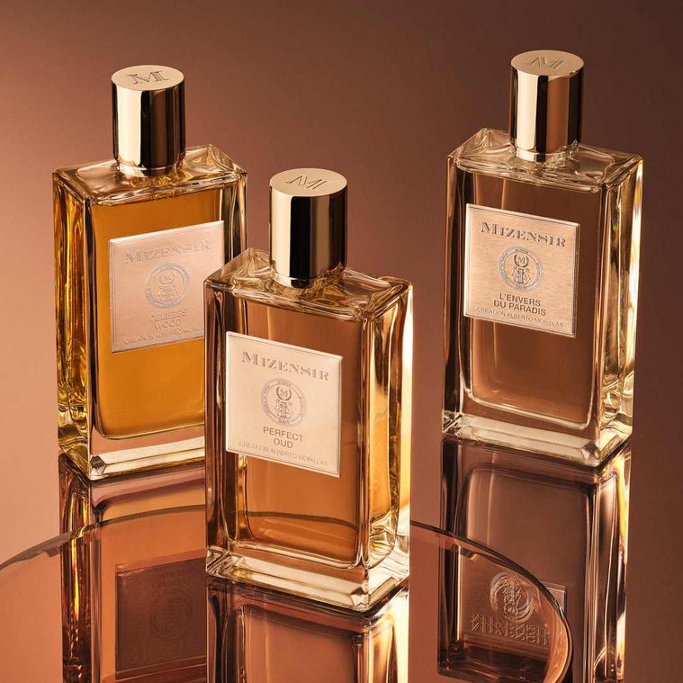 Mizensir Fragrance and Perfume bottles sit on a reflected Bronze surface. The reflections cast a rich bronzy gradient across the image. 