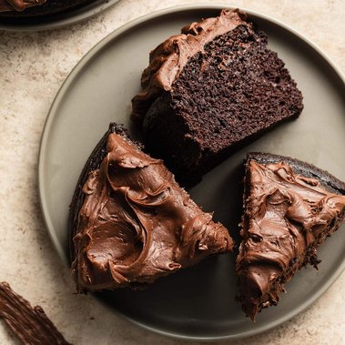 Three pieces of chocolate cake with chocolate frosting arranged on a brown plate.