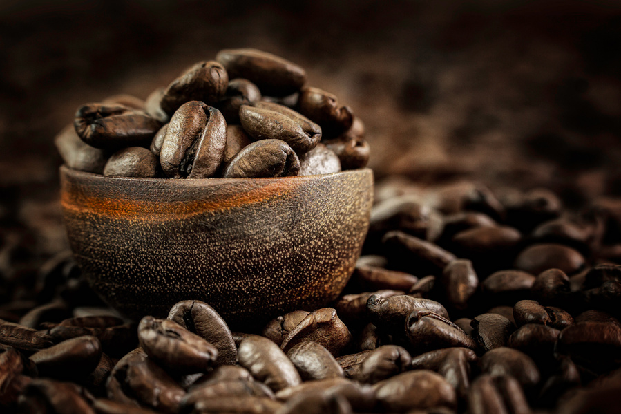 tiny wooden ladle filled with coffee beans in a bed of coffee beans