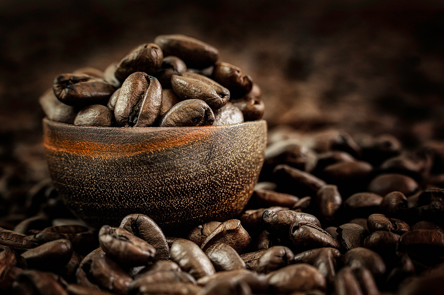 tiny wooden ladle filled with coffee beans in a bed of coffee beans