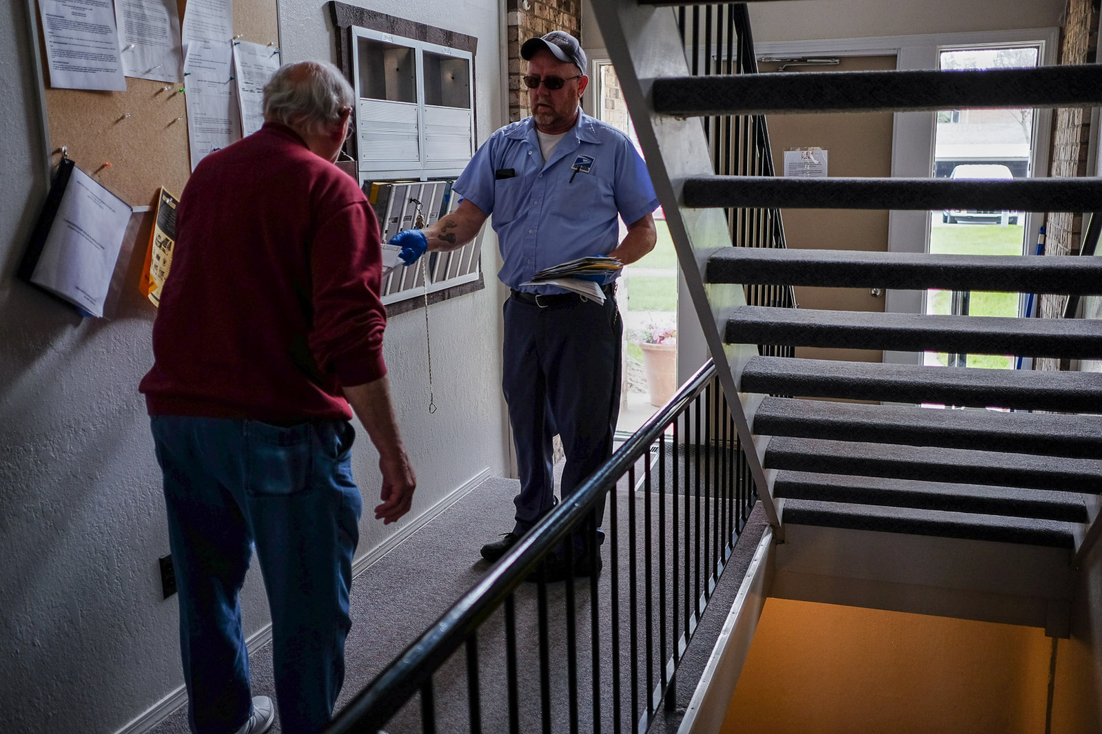 Mark Swan, a USPS letter carrier and President of the National Association of Letter Carrier’s 74th branch in Saginaw, hands a customer his mail on Saturday, April 25, 2020 in Saginaw, Mich.