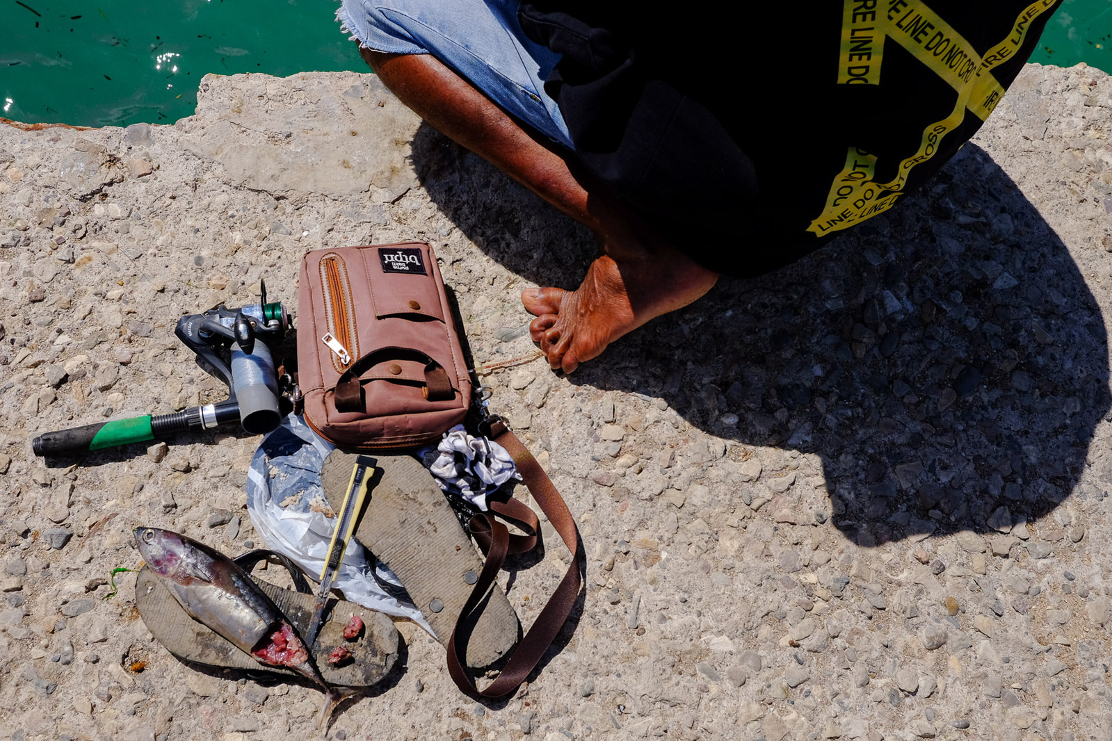 A man fishes from a concrete pier on May 21, 2019 in Kupang, Indonesia.