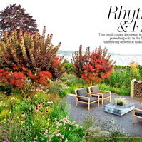 A coastal garden by Adam Woodruff with naturalistic plantings, smokebush trees, and a modern patio overlooking the water.