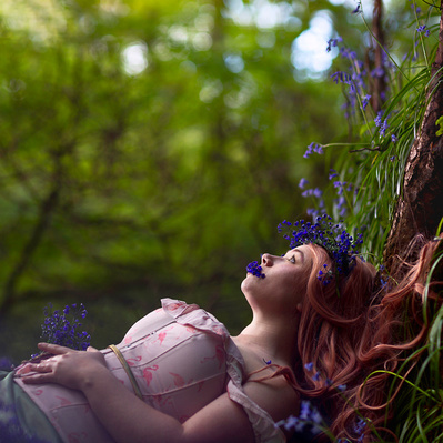 Photographic art of A person lying down in the woods, surrounded by bluebells. With bluebells growing out her mouth.