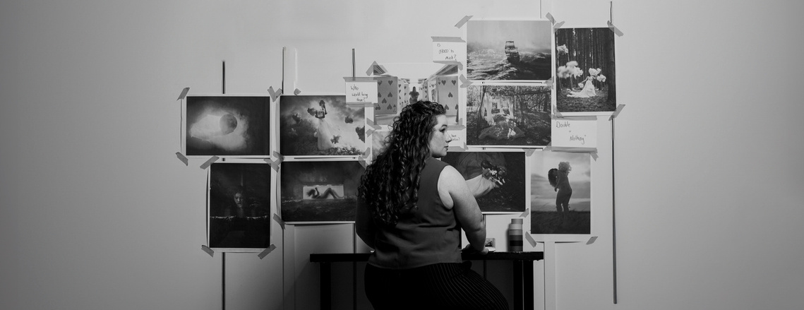 A artist sitting at a table looking at photographs she has created.