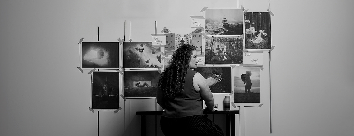 A artist sitting at a table looking at photographs she has created.
