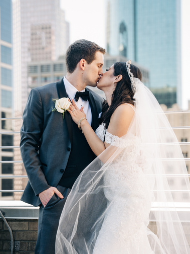 A newlywed couple kissing on a rooftop.