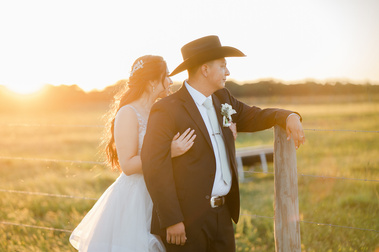 A bride and groom looking off into the distance in a rural area.