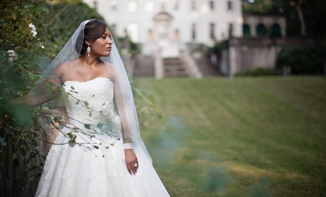 A black bride in white gown with an updo wedding veil. photographed at the Swan House in Atlanta Georgia
