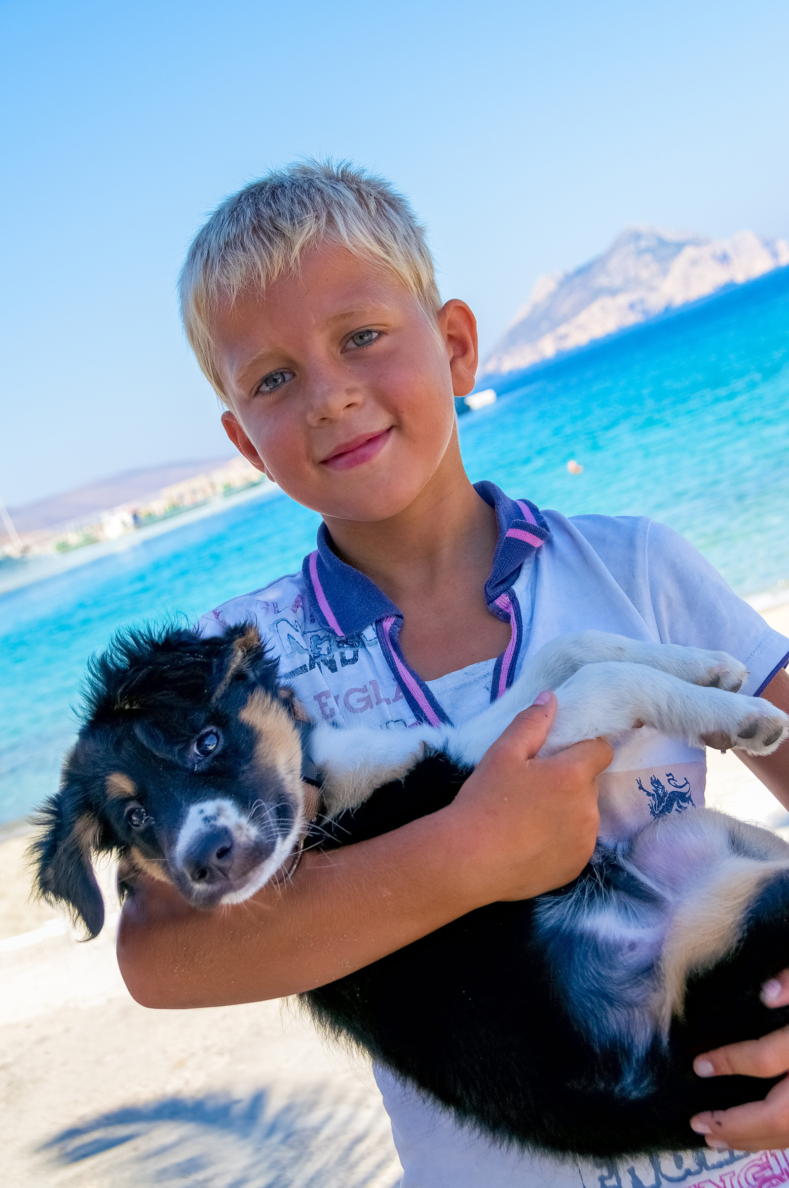 Blonde greek boy holding puppy Egiali Amorgos Island Greek Islands Greece