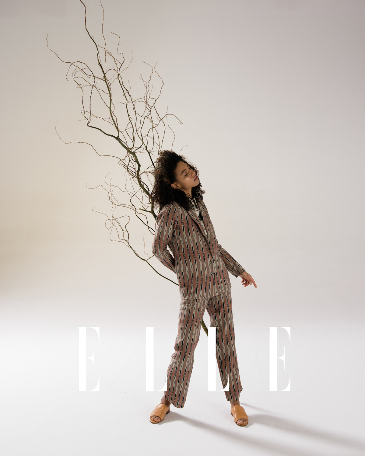 Black woman holding a branch in sustainable clothing.