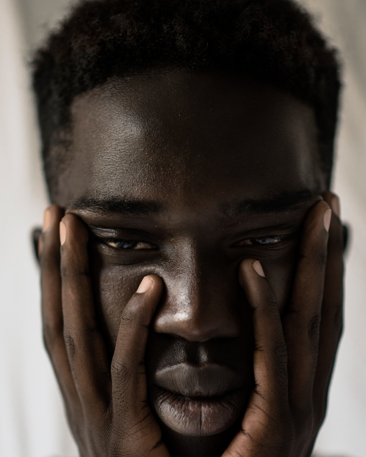 Face of a sad black man with his hands on the cheeks.