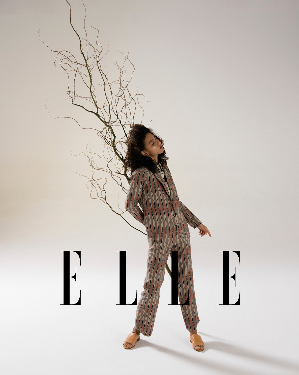 Black woman holding a branch in sustainable clothing.