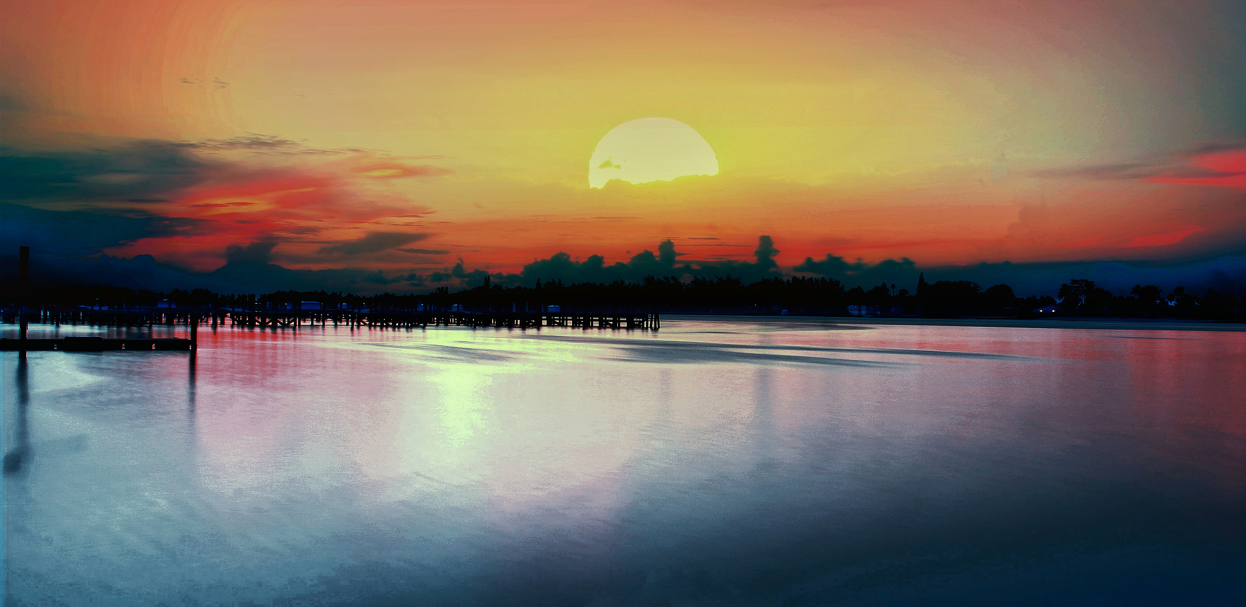 Immerse yourself in the ethereal beauty of this breathtaking sunset, where the golden sun melts into the horizon, casting hues of crimson, amber, and deep indigo across the still waters.