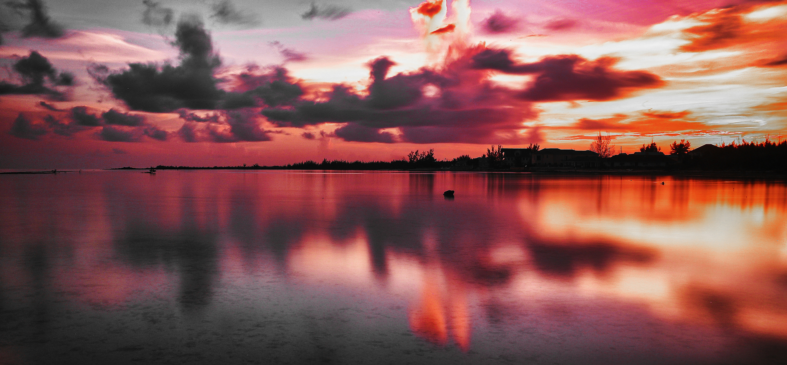 Embers of the Horizon” captures a breathtaking sunset over tranquil waters, where fiery hues of red, orange, and magenta blend seamlessly into the sky and reflect across the glassy surface below. This fine art photograph evokes both passion and peace, off