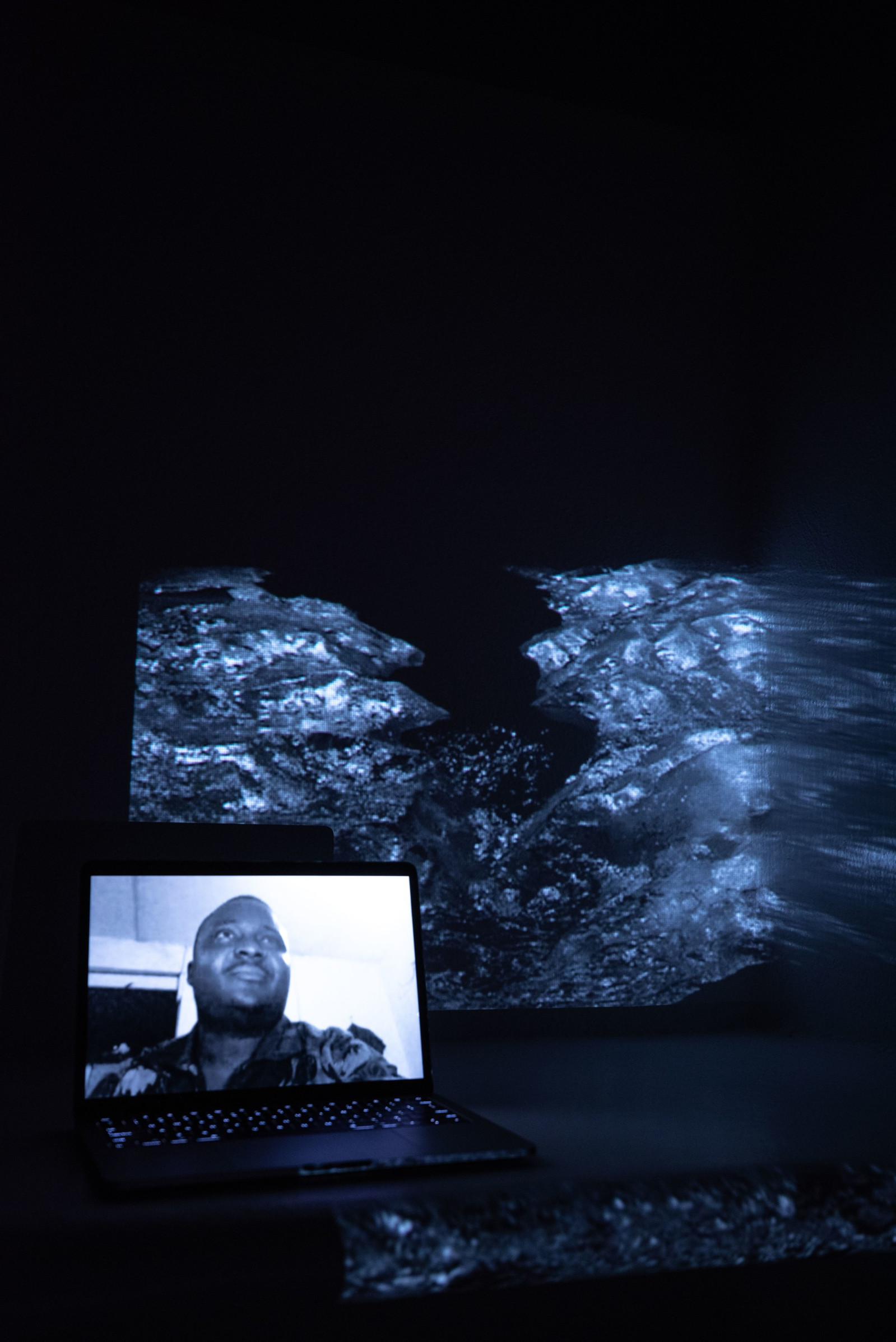 Digital portrait on a laptop screen with an image of a melting glaciar in high contrast, projected into the background.