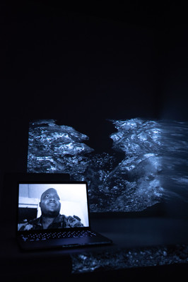 Digital portrait on a laptop screen with an image of a melting glaciar in high contrast, projected into the background.