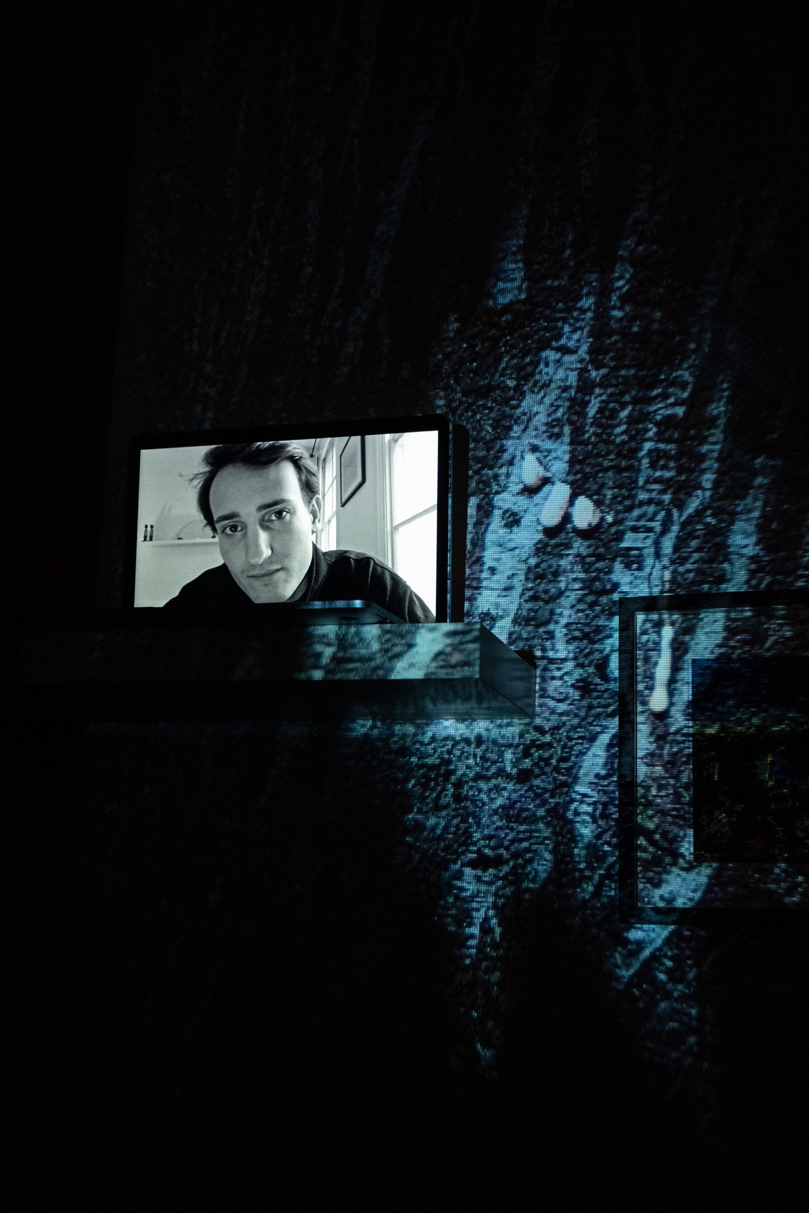Digital portrait on a laptop screen with an image of a tree bark dripping a white liquid into the background.