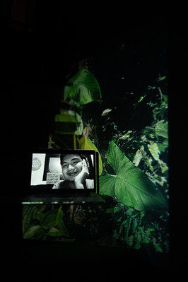 Digital portrait on a laptop screen with an image of wild leaves up close-up projected into the background.