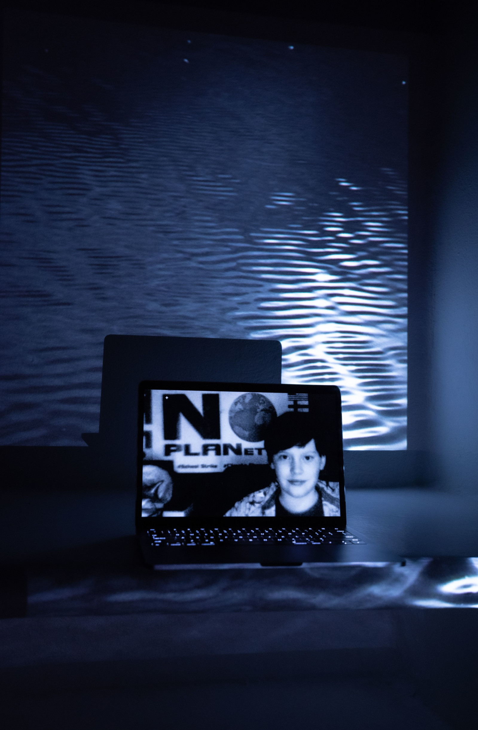 Digital portrait on a laptop screen with an image of water ripples projected into the background.