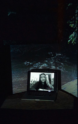 Digital portrait on a laptop screen with an image of a dark river projected into the background.