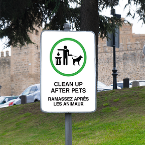 A Clean up after your pets sign on a pole on the park grounds.