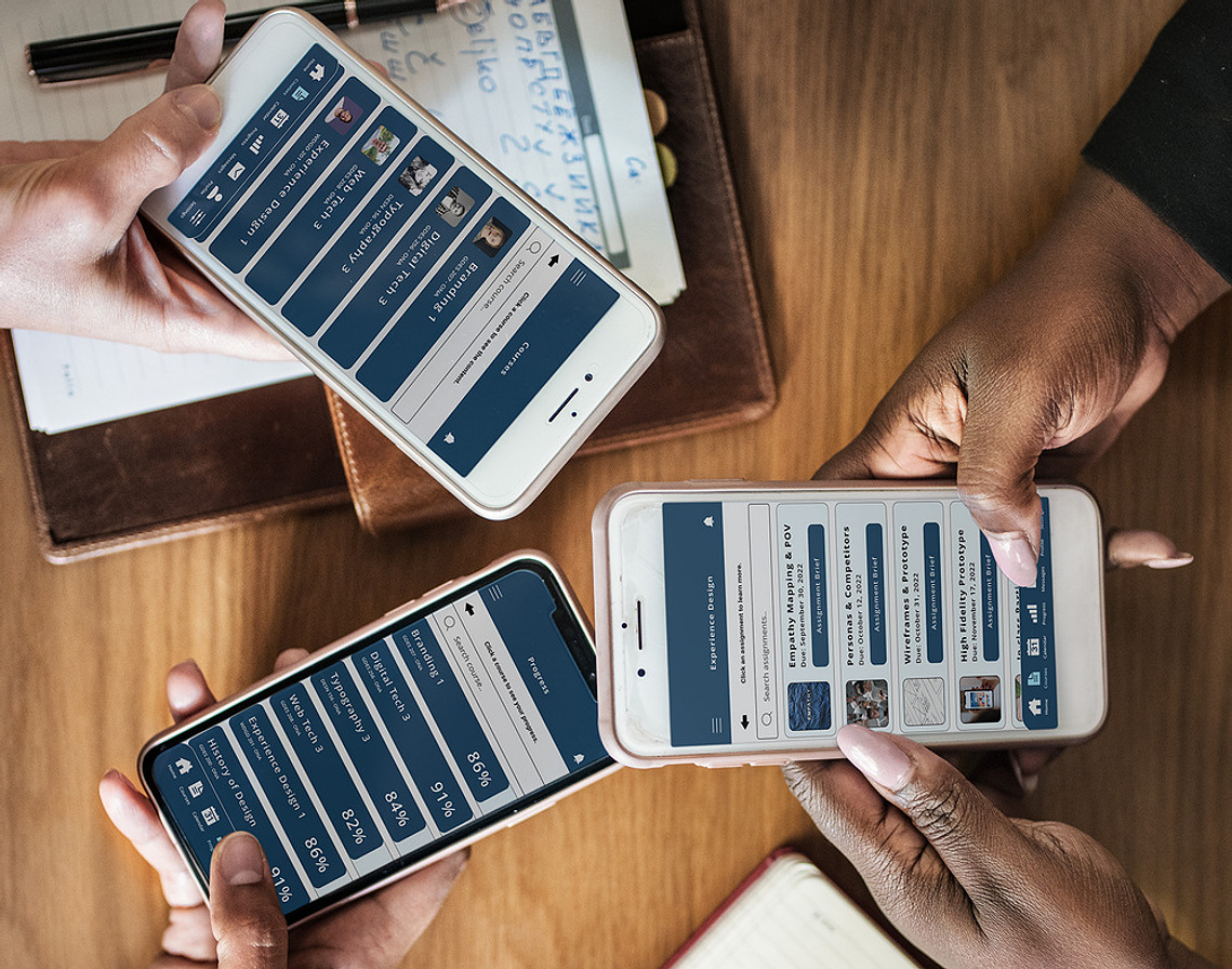 Three people around a table showing their phones to each other with the new app design on the screens.