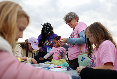 Laura Howell and her two daughters, Izora, 2, left, and Karen, 8, right, of Sheraton make friendship bracelets at the Harris rally on Monday, Nov. 4, 2024, at Carrie Blast Furnaces National Historic Landmark in Swissvale.