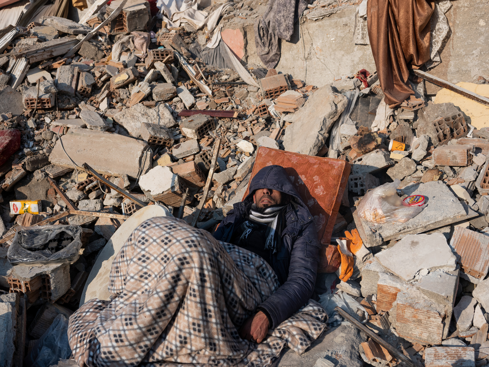 Sleeping in the rubble ruins of his home - former residents of apartment blocks destroyed by the earthquake, wait next to rescue workers, for news on their loved ones.