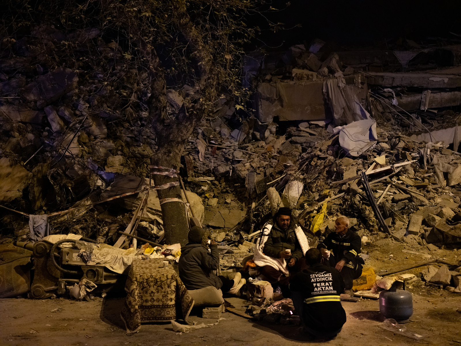 Sleeping in the rubble ruins of his home - former residents of apartment blocks destroyed by the earthquake, wait next to rescue workers, for news on their loved ones.